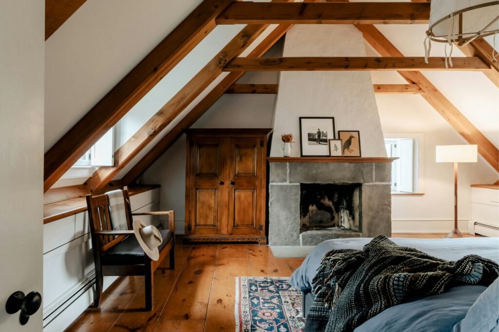 A bedroom with a made bed beside a fireplace