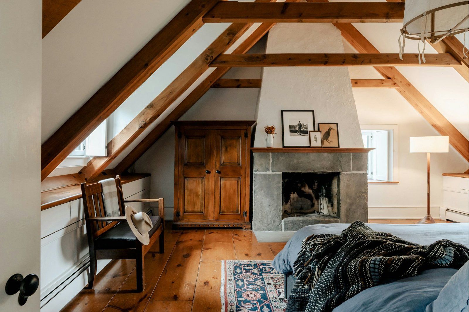 A bedroom with a made bed beside a fireplace