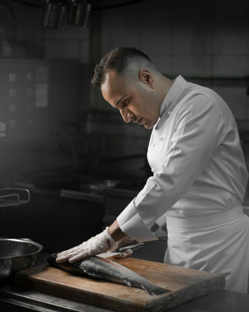 A chef in whites preparing fish at the pass