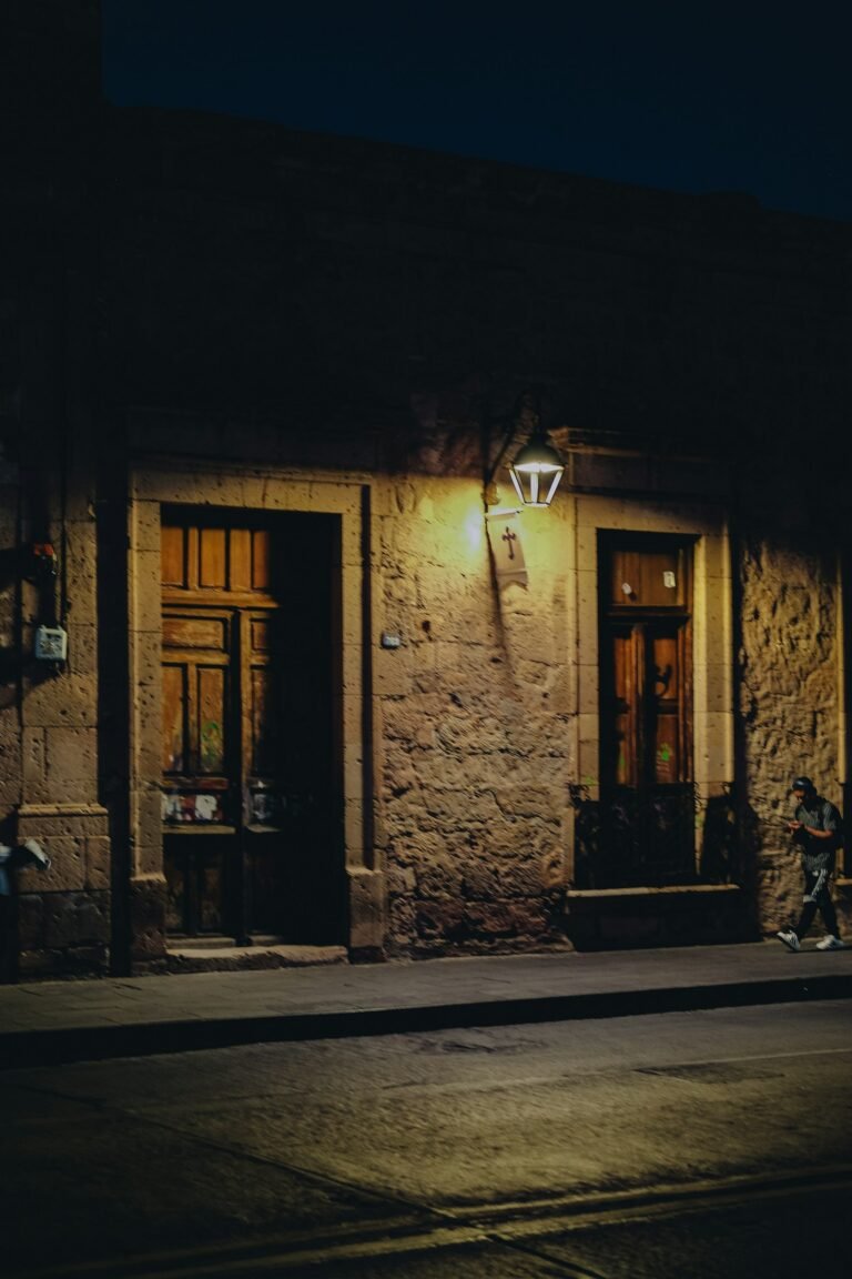 A stone building lit by a lantern on a dark street