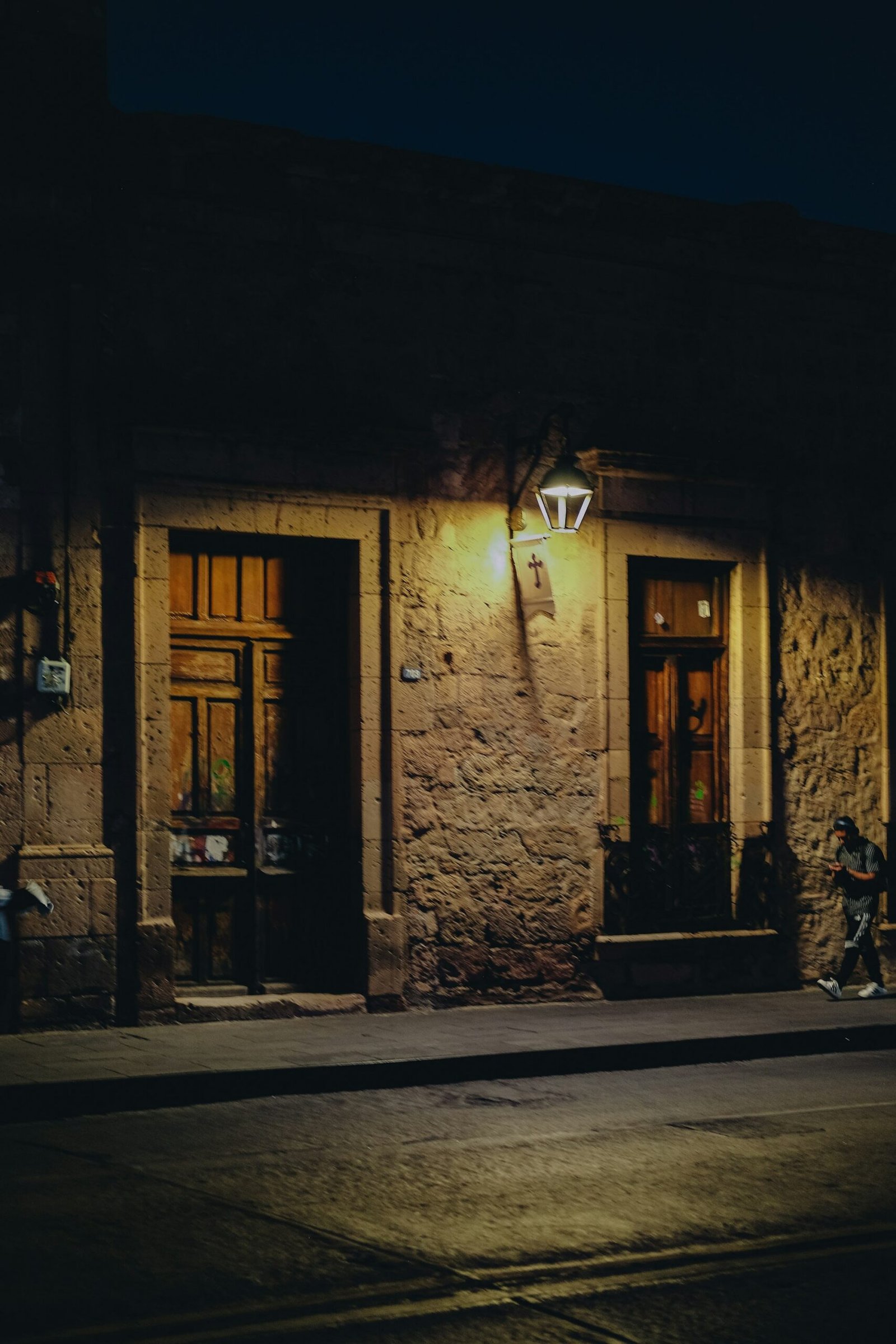A stone building lit by a lantern on a dark street