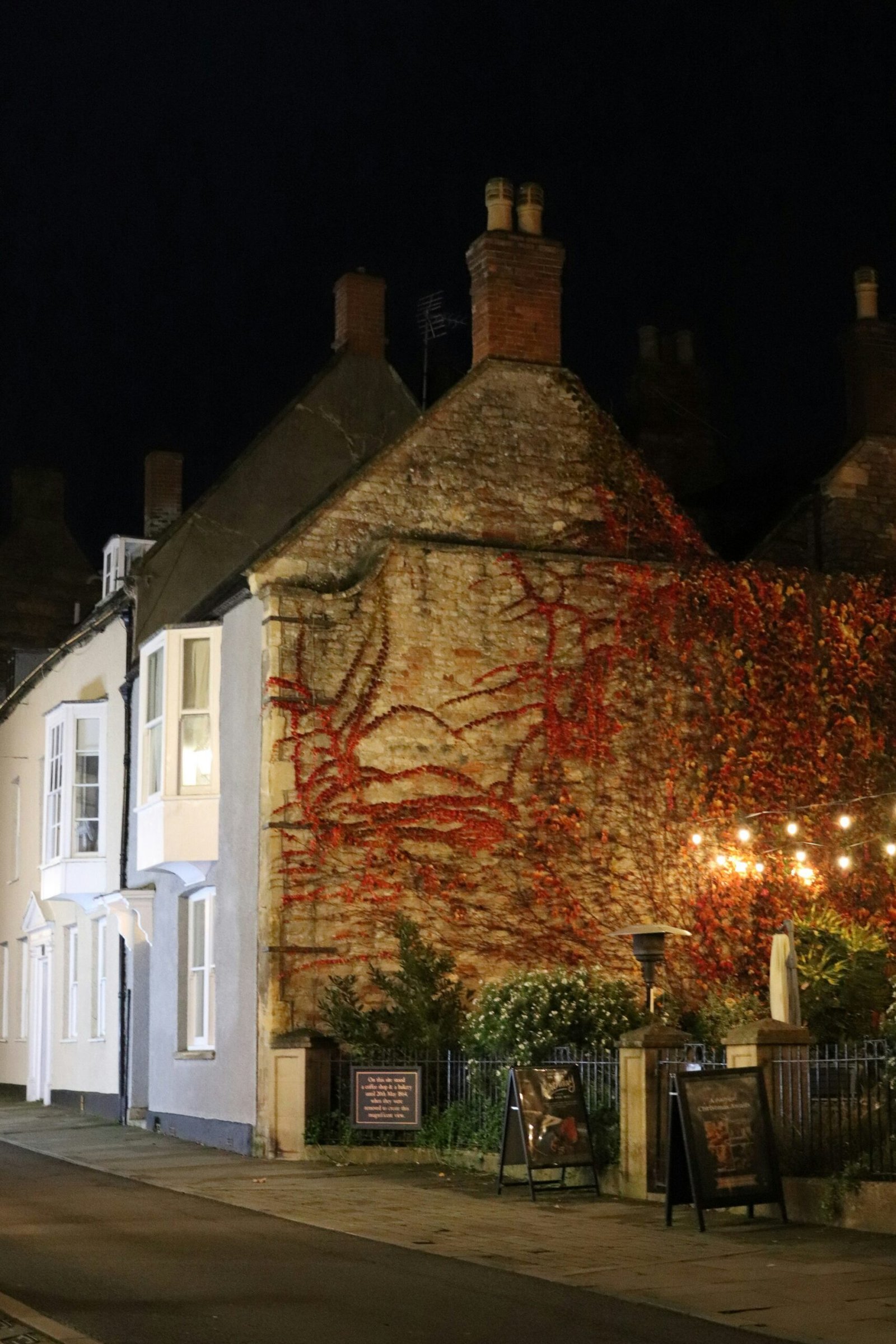 An ivy-covered house lit with warm lights at night