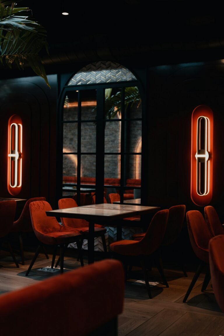 Round tables by tall windows in a dark dining room