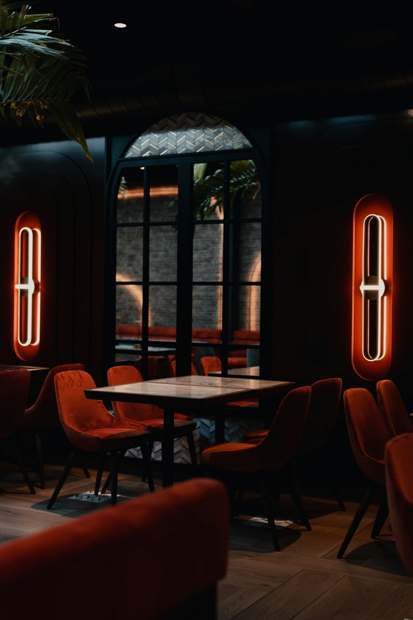Round tables by tall windows in a dark dining room