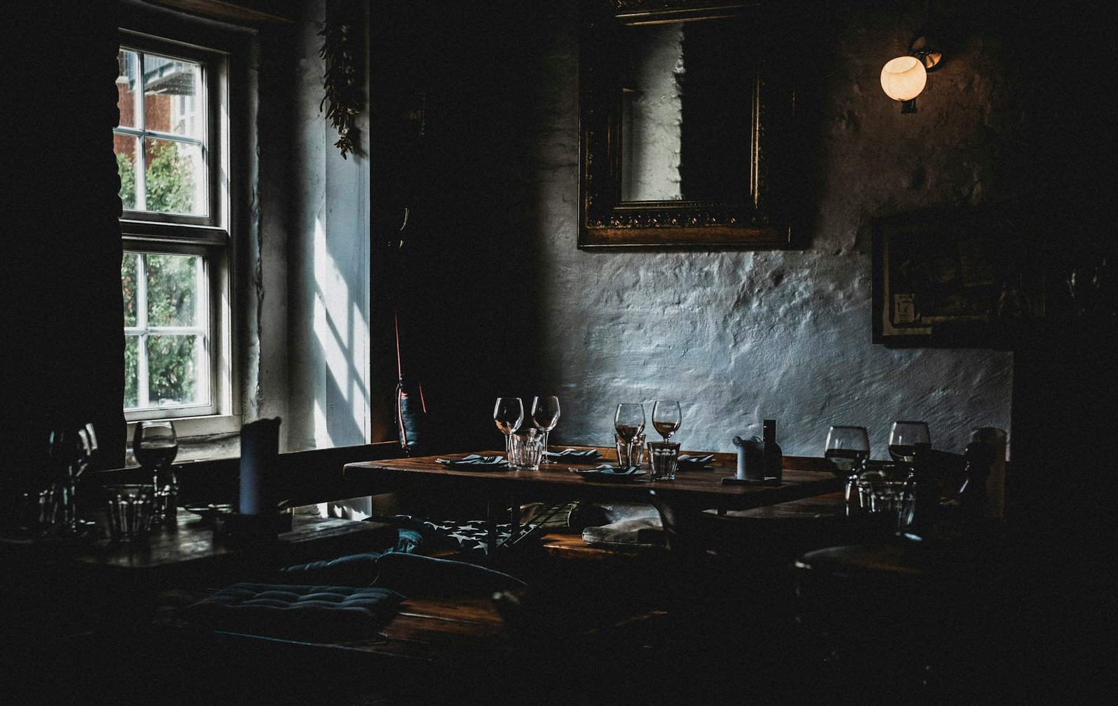 Wine glasses on a table near a window in a dark room
