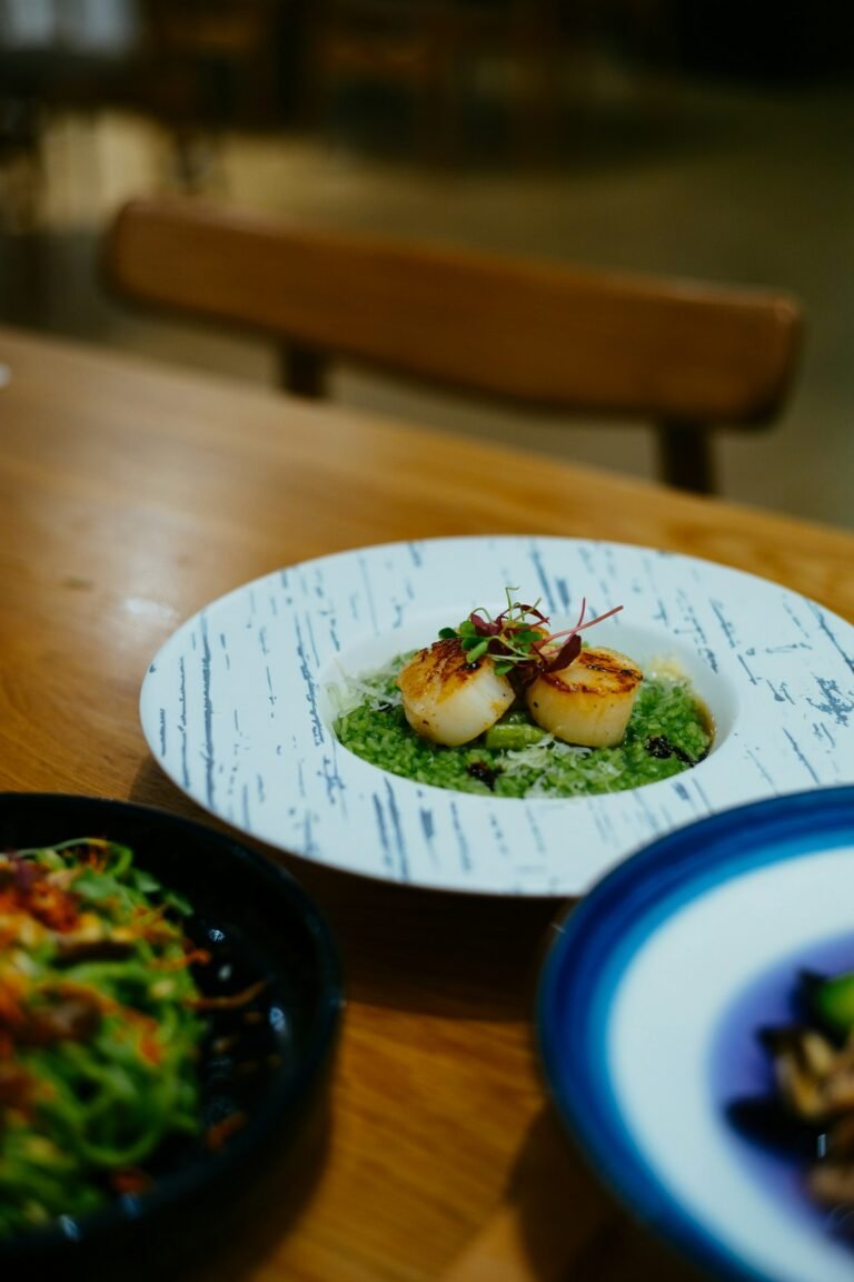 Seared scallops in a green sauce on a white plate